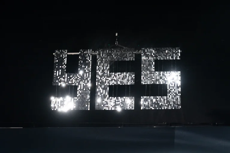 Ein großes, leuchtendes "YES" aus Glühbirnen hängt an einem dunklen Himmel. Es reflektiert das Licht in alle Richtungen.