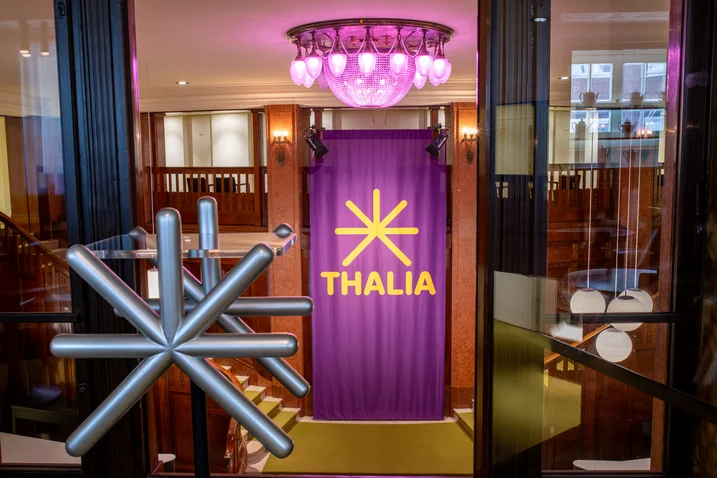 Entrance to a theater featuring a large purple banner with "THALIA" and a stylized star decoration.